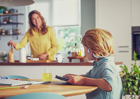 Gutt som ser p&aring; video mens han bruker tr&aring;dl&oslash;se Philips-barnehodetelefoner som sitter p&aring; &oslash;ret