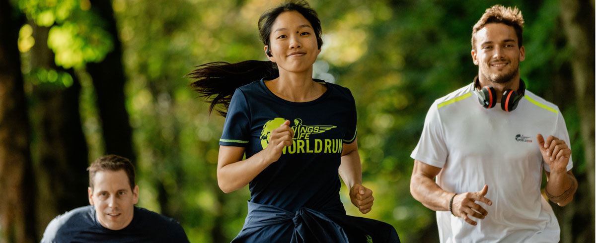 Tre Wings for Life World Run-deltakere l&oslash;per med glede og bruker Philips-sportshodetelefoner.